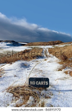no carts sign on a snow covered links golf course in ireland in snowy winter weather