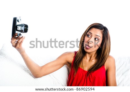 Young Asian Indian girl with old camera, taking photos of herself, sticking tongue out to camera,