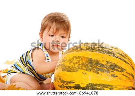 Toddler playing with large pumpkin