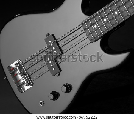 detail of a black bass guitar in dark back