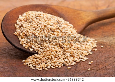 Organic natural sesame seeds on wooden spoon Royalty-Free Stock Photo #86999342
