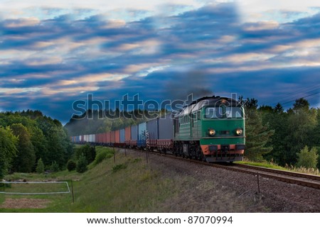 Freight train hauled by the diesel locomotive passing the forest