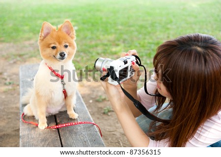 beautiful asian woman taking dog's photo in the park
