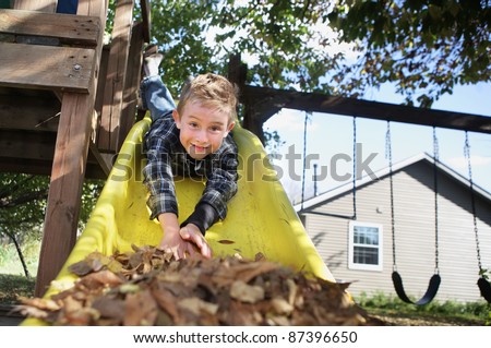 Happy Boy sliding head first down a slide Royalty-Free Stock Photo #87396650
