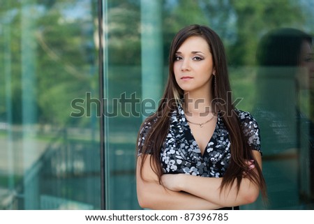 seriously brunette woman looking at camera, standing near glass wall