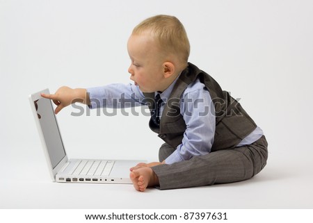 A cute baby boy is dressed in smart business clothes and is with his laptop ready for work. Studio shot Isolated on white.