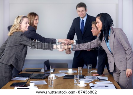 Welcome handshake before business meeting, 5 young business people at conference table