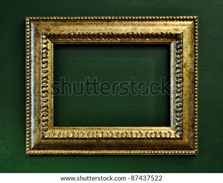 Gold empty picture frame border on green wall background