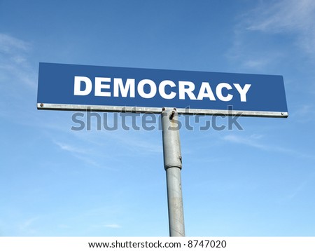 Metal signpost spelling Democracy over blue sky