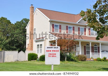 Short Sale Realtor Sign on Two Story Home Front Yard in Suburban Residential Neighborhood Sunny Blue Sky Day