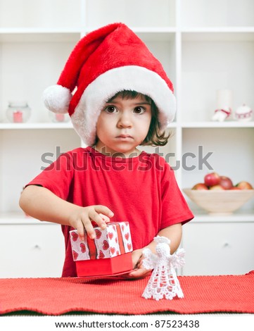 Cute little toddler girl opening a Christmas present
