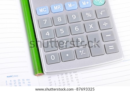 Calculator and pencil on notebook, closeup