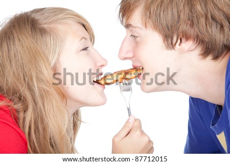hungry teenage couple eating cakes, white background