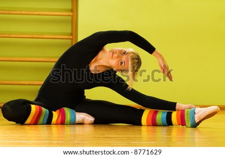 Ballet dancer doing stretching exercise on a floor