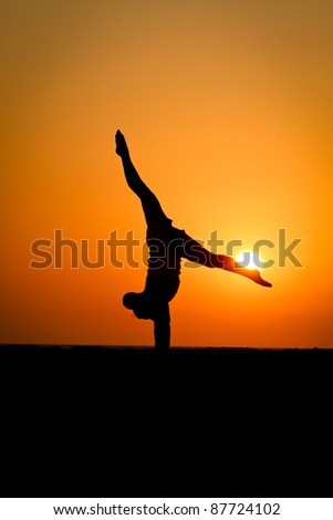 silhouette of gymnast in sunset at beach