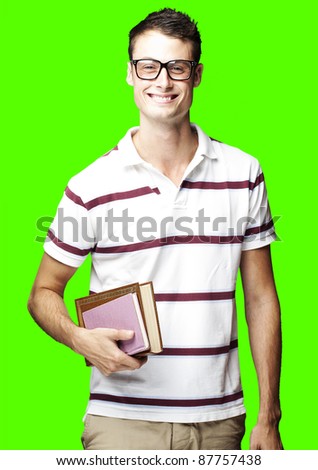 portrait of young man smiling and holding books against a removable chroma key background