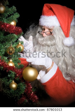 Carefulness Santa Claus decorate Christmas tree at night. Christmas decoration of the Christmas tree.