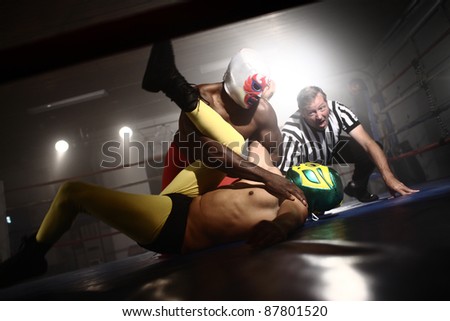 Masked wrestlers and referee in ring