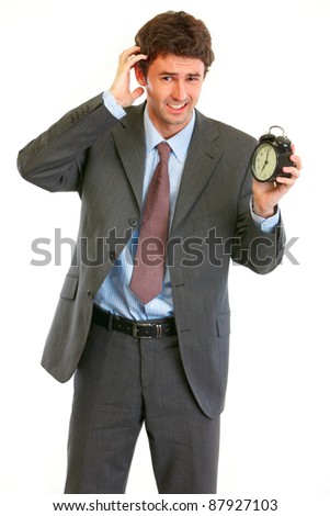 Concerned about time modern businessman with alarm clock isolated on white