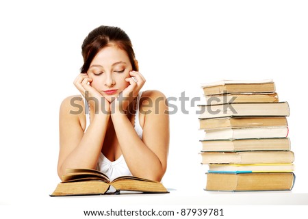 Young pretty caucasian girl sitting and reading a book near the pile of books.