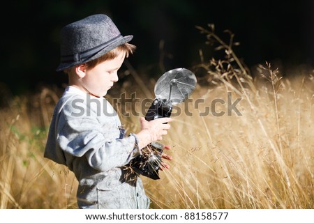 Stylish small boy with retro camera photographing outdoors on sunny autumn day