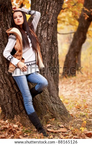 brunette woman posing near tree in autumn park