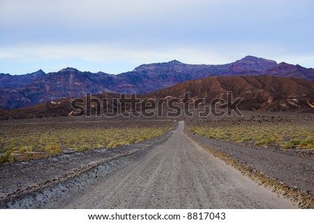 Desert road landscape with multicolored yellow clay and salt mineral deposits in geological formations of Death Valley National Park