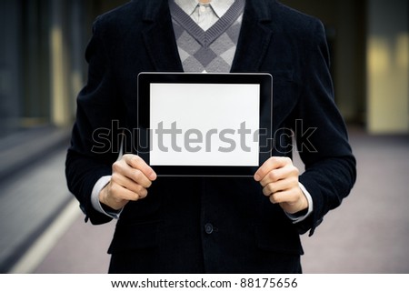Business man holding and shows touch screen tablet pc with blank screen.