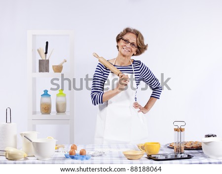 Senior woman at her kitchen showing you the rolling pin Royalty-Free Stock Photo #88188064