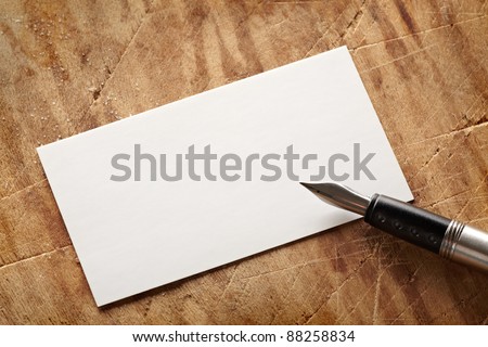 Blank business (visit) card on old wooden table with vintage fountain pen.