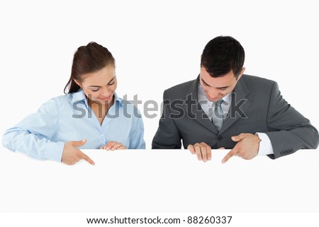 Business partners looking and pointing at sign they are holding against a white background