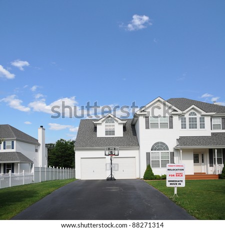 Realtor Short Sale Sign on Front Yard Lawn of Beautiful White Suburban Home with Basketball Hoop in Front of Two Car Garage on Sunny Blue Sky Day