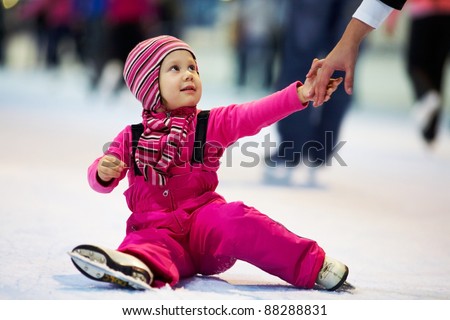 Mothers hand help little cute girl on the rink