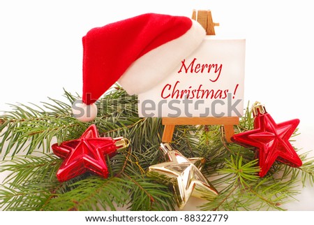 christmas greetings written on white canvas of wooden easel with hanging santa hat