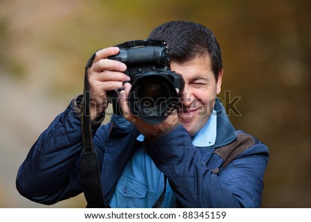Professional nature photographer taking photos in the forest in an autumn day