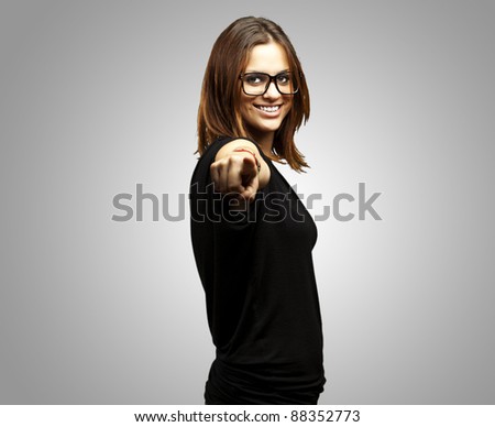portrait of young woman pointing with glasses over grey background
