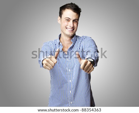 portrait of a handsome young man doing good symbol over black background
