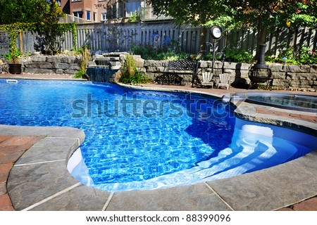 Residential inground swimming pool in backyard with waterfall and hot tub Royalty-Free Stock Photo #88399096