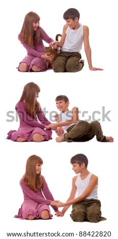 A sister and brother play a game together as they sit beside each other on the floor.