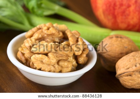 Raw walnut halves (lat. Juglans regia) with celery and apple, which are the main ingredients of the Waldorf Salad (Very Shallow Depth of Field, Focus on the front of the nut)