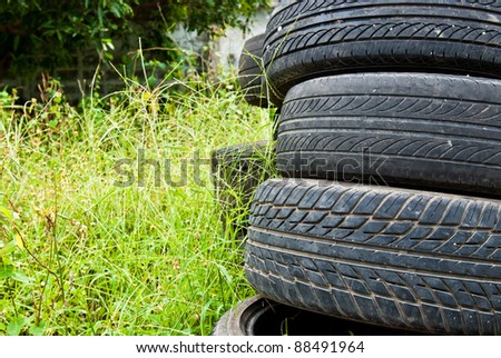 Old road tires stacked on grass land as background