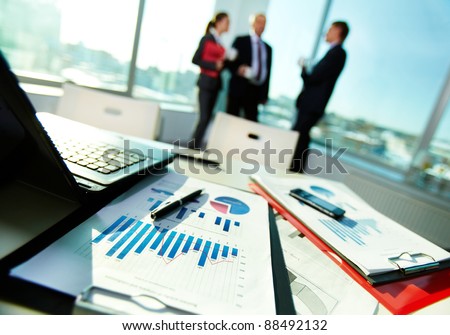 Image of business documents on workplace with three partners interacting on background Royalty-Free Stock Photo #88492132