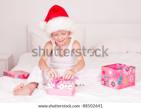 happy little boy celebrating Christmas and opening presents on the bed at home