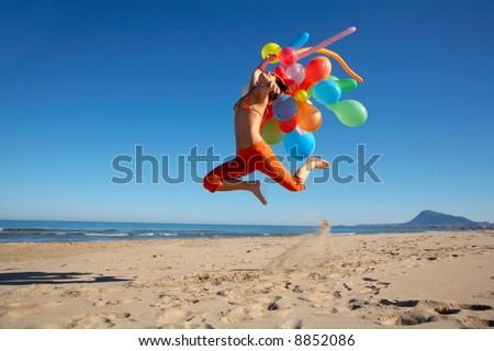 happy teen girl jumping on the beach with different colored balloons