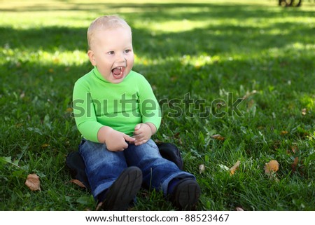 Happy little boy having fun in green summer park