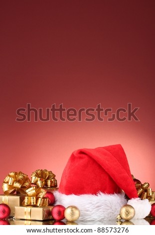 Beautiful Christmas hat, gifts and Christmas balls on red  background