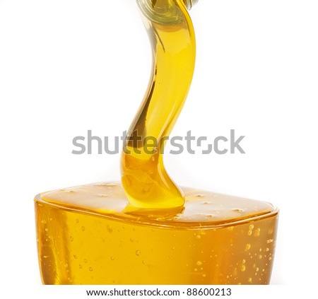 Gold flowing honey, closeup on white background