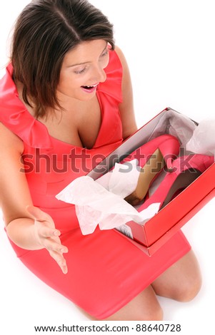 A picture of a happy surprised woman holding her shoes over white background