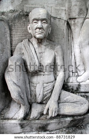 Statue of buddhist monk on the wall of monument in Santichaiprakan Park, Bangkok, THailand