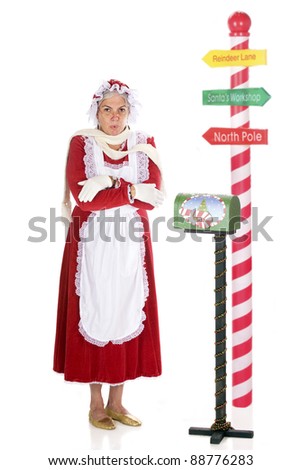Mrs. Claus shivering by a Christmas-decorated mail box and a North Pole sign.  Isolated on white.